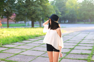 Rear view of woman standing on footpath