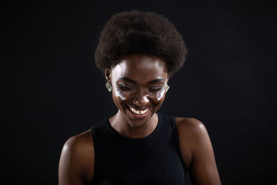 Portrait of smiling young woman against black background