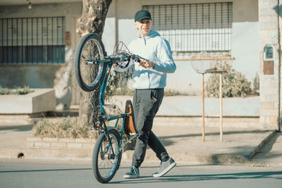 Young man holding his bicycle in the street