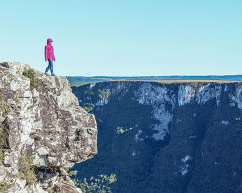 Rear view of man standing on rock against sky