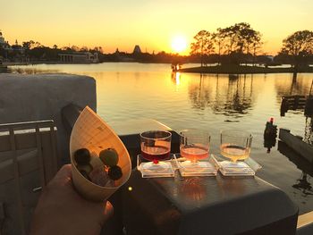 People on lake against sky during sunset