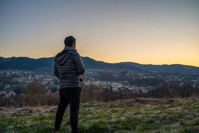 Wide angle shot of a man from behind looking at a landscape consists of mountain during sunrise