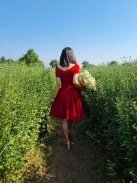 Rear view of woman standing on field against sky