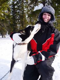 Portrait of woman with dog standing against trees during winter