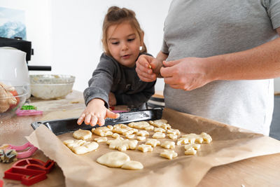 Midsection of father with daughter preparing cookies at home