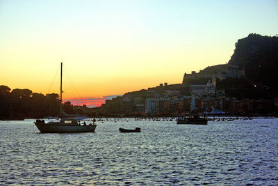 Boats sailing on river against clear sky during sunset