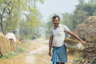 Portrait of smiling young man standing at village holding basket