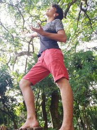 Low angle view of girl standing against tree