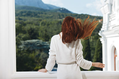 Rear view of woman looking through window