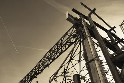 Low angle view of silhouette cranes against sky