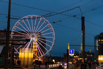 Low angle view of illuminated ferris wheel against blue sky