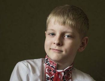 Portrait of cute boy in traditional clothing against gray background