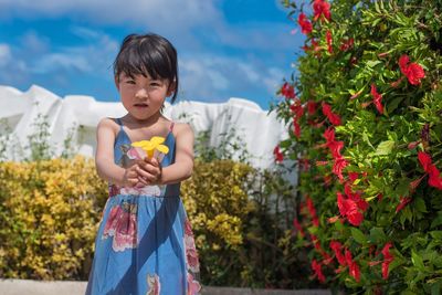 Portrait of cute girl holding yellow flower at park