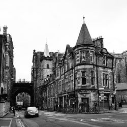 Cars on city street by buildings against clear sky