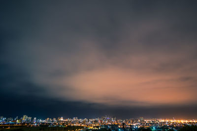 Illuminated buildings in city against sky at sunset