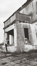 Woman in old building against sky