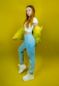 Portrait of smiling woman standing against yellow background