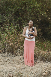 Portrait of young mother holding newborn age daughter outside