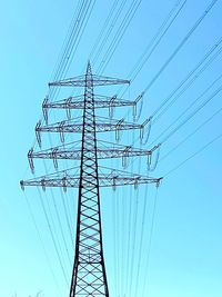 Low angle view of electricity pylon against blue sky