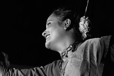 Low angle view of smiling mid adult woman wearing traditional clothing dancing in room