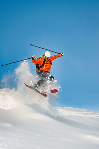 Low angle view of people skiing on snow covered landscape