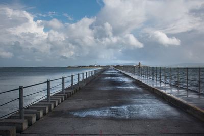 Pier on sea against cloudy sky