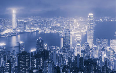 High angle view of illuminated cityscape and river against sky at dusk