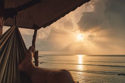 Man relaxing in swimming pool against sea during sunset