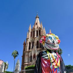 Low angle view of statue against building against clear blue sky