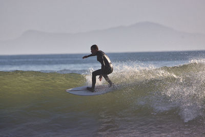 Full length of man surfing in sea against sky