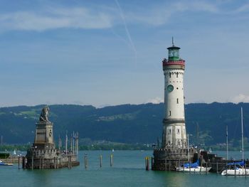 Lighthouse on building by sea against sky