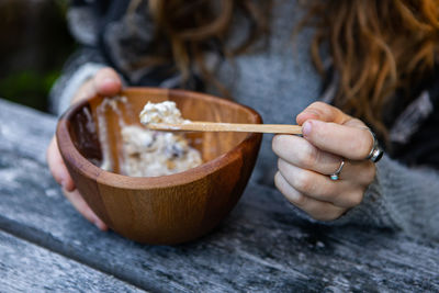Midsection of woman eating ice cream in bowl