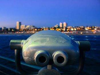 Close-up of coin-operated binoculars against cityscape