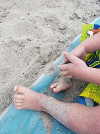 High angle view of hand on sand at beach