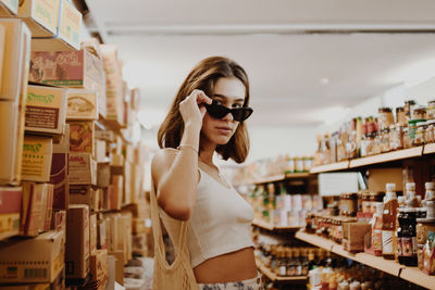 Young woman wearing sunglasses standing at store