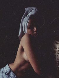 Side view of shirtless young woman standing at night