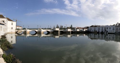 Bridge over river by buildings against sky in city