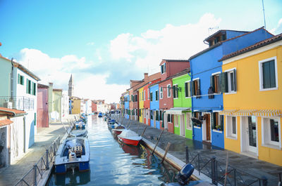 Boats in canal amidst buildings in city against sky