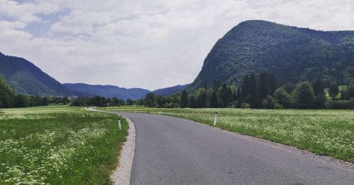 Empty road along landscape and mountains against sky