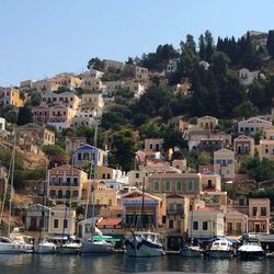 Sailboats in sea by townscape against sky