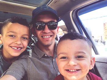 Portrait of smiling boy with sunglasses in car