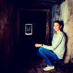 Portrait of smiling young woman sitting against wall