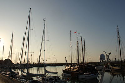 Boats moored in harbor at sunset