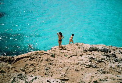 High angle view of friends on rock by sea