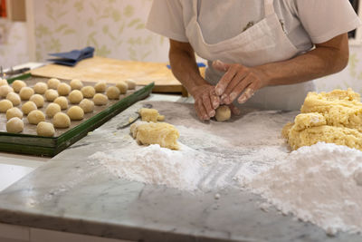 Working with hands of uncooked dough with flour and eggs for making round cakes.