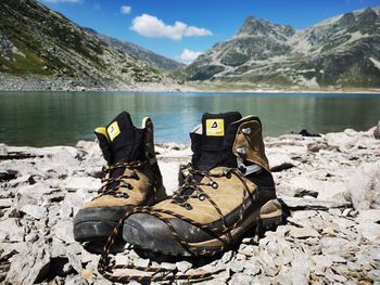 Low section of shoes by lake against mountain range