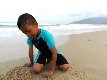 Boy on shore at beach against sky