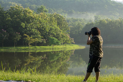 Rear view of woman photographing in park