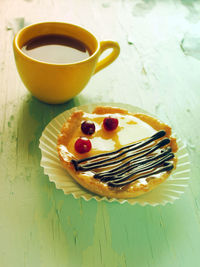 High angle view of coffee cup and tart on wooden table