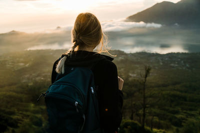 Rear view of woman looking at mountains against sky